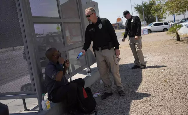 Mark Paulson, a Public Response and Code Enforcement officer, hands out cold water, Wednesday, July 10, 2024, during a heat emergency in Henderson, Nev. (AP Photo/John Locher)