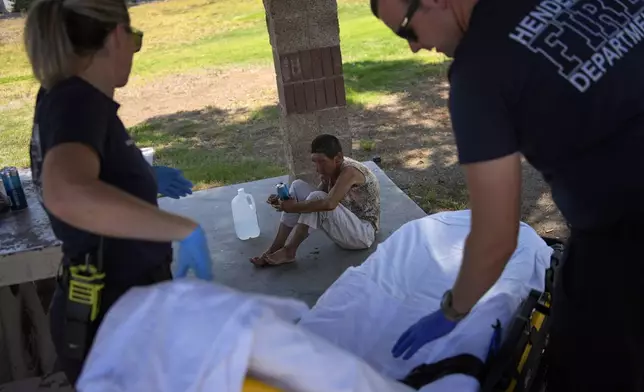 Members of the Henderson Fire Department prepare to take Deb Billet, 66, to the hospital for heat-related symptoms, Wednesday, July 10, 2024, in Henderson, Nev. Billet has been living on the street. (AP Photo/John Locher)