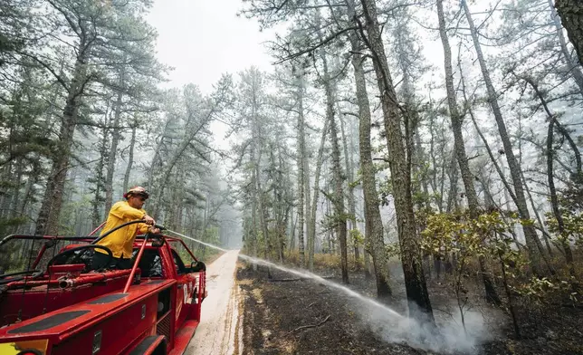 This Friday, July 5, 2024 image provided by the New Jersey Department of Environmental Protection shows members of the New Jersey Forest Fire Service battling a forest fire in Tabernacle, N.J. The fire had burned 4,000 acres and was 75% contained as of Monday July 8. (New Jersey Department of Environmental Protection via AP)