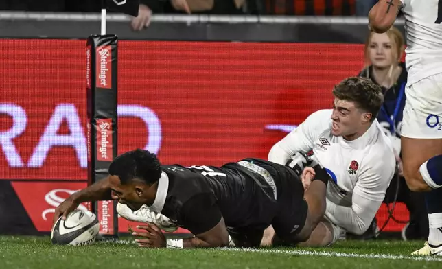 Sevu Reece of New Zealand, left, scores a try against England during their rugby union test match in Dunedin, New Zealand, Saturday July 6, 2024. (Andrew Cornaga/Photosport via AP)