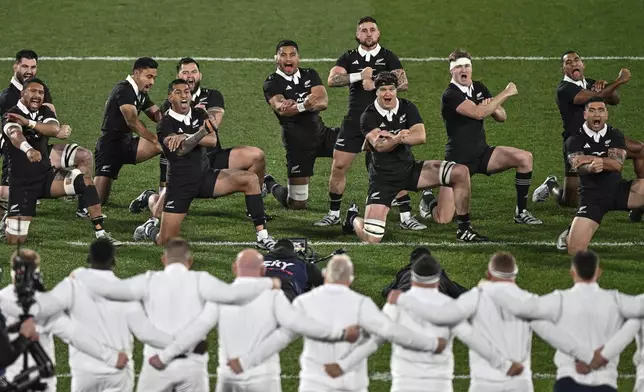 England's players lock arms as New Zealand perform the haka ahead of their rugby union test match in Dunedin, New Zealand, Saturday July 6, 2024. (Steve McArthur/Photosport via AP)