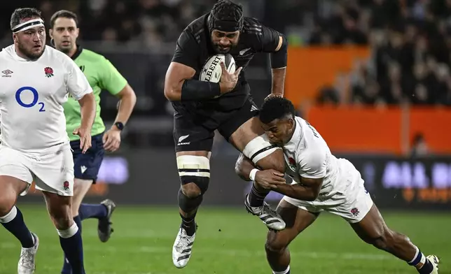 New Zealand's Patrick Tuipulotu, center, is tackled by England's Immanuel Feyi-Waboso during their rugby union test match in Dunedin, New Zealand, Saturday July 6, 2024. (Andrew Cornaga/Photosport via AP)