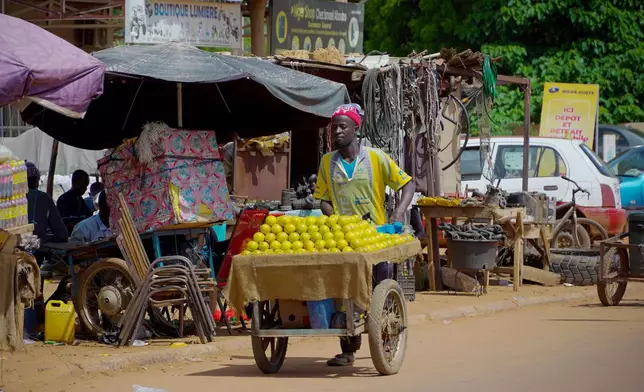 A man sells oranges on the street in Niamey, Niger, Wednesday, July. 24, 2024. One year has passed since a dramatic coup in Niger. (AP Photo/Omar Hama)