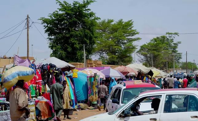 Pedestrian shops at a market in Niamey, Niger, Wednesday, July. 24, 2024. One year has passed since a dramatic coup in Niger. (AP Photo/Omar Hama)