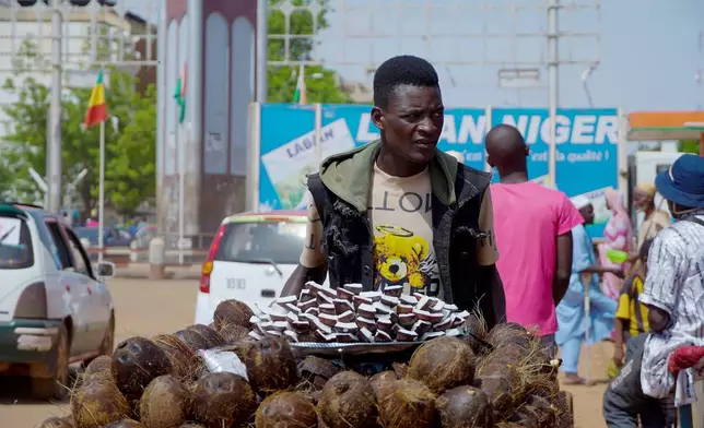 A man sells coconut on the street in Niamey, Niger, Wednesday, July. 24, 2024. One year has passed since a dramatic coup in Niger.(AP Photo/Omar Hama)