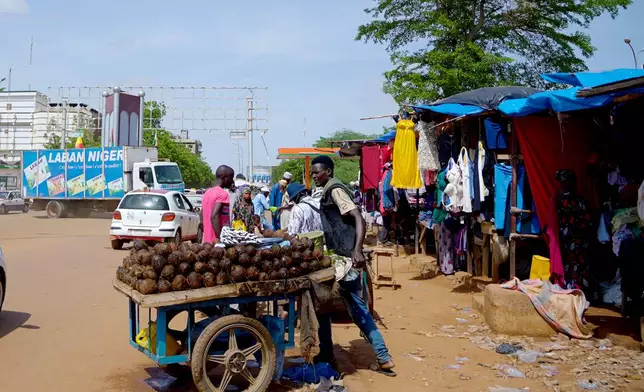 A man sells coconut on the street in Niamey, Niger, Wednesday, July. 24, 2024. One year has passed since a dramatic coup in Niger. (AP Photo/Omar Hama)