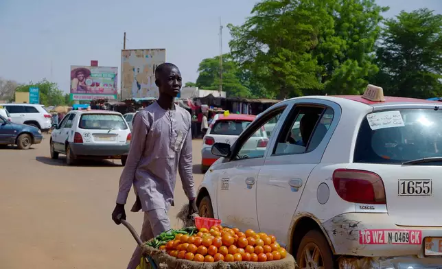 A man sells tomatoes on a street in Niamey, Niger, Wednesday, July. 24, 2024. One year has passed since a dramatic coup in Niger. (AP Photo/Omar Hama)