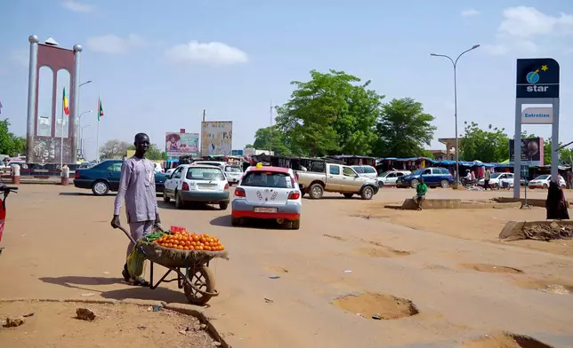 A man wheels tomatoes to sell on a bad road in Niamey, Niger, Wednesday, July. 24, 2024. One year has passed since a dramatic coup in Niger. (AP Photo/Omar Hama)