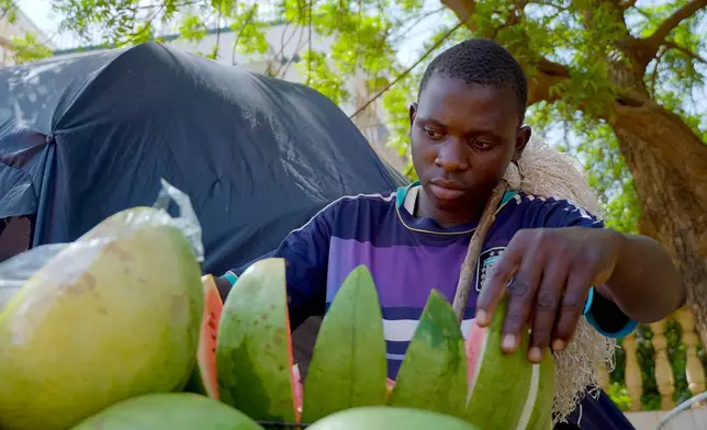 A man sells watermelon on the street in Niamey, Niger, Wednesday, July. 24, 2024. One year has passed since a dramatic coup in Niger. (AP Photo/Omar Hama)