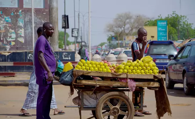 A man sells oranges and apples on the street in Niamey, Niger, Wednesday, July. 24, 2024. One year has passed since a dramatic coup in Niger. (AP Photo/Omar Hama)