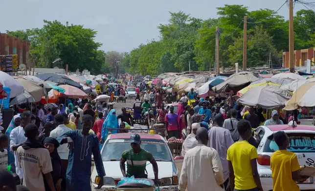 Pedestrian shops at a market in Niamey, Niger, Wednesday, July. 24, 2024. One year has passed since a dramatic coup in Niger. (AP Photo/Omar Hama)