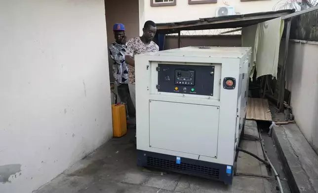 A worker inspects a generator used by Nature's Treat Cafe to run their business in Ibadan, Nigeria, Monday, May 27, 2024. Households and businesses often use polluting gasoline and diesel-run backup private generators. But as fuel prices rise, businesses like Nature's Treat Cafe face unsustainable generator costs, prompting a push for affordable solar solutions. (AP Photo/Sunday Alamba)
