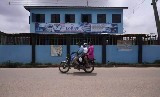 A motorcycle taxi rides past Lorat Nursery and Primary School in Ibadan, Nigeria, Tuesday, May 28, 2024. The lack of reliable electricity severely affects education and businesses in Nigeria. (AP Photo/Sunday Alamba)
