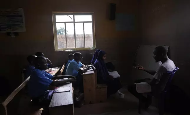 Students of Excellent Moral School attend a lesson in a window-lit classroom in Ibadan, Nigeria, Tuesday, May 28, 2024. Schools like Excellent Moral operate in darkness due to zero grid access, depriving students of essential tools like computers. (AP Photo/Sunday Alamba)