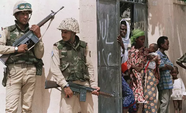 FILE - Somalis watch as Pakistani soldiers from the United Nations peacekeeping forces sweep through their neighborhood on June 9, 1993, in Mogadishu, in search of snipers responsible for the ambush of U.N. soldiers. (AP Photo/Kathy Willens, File)