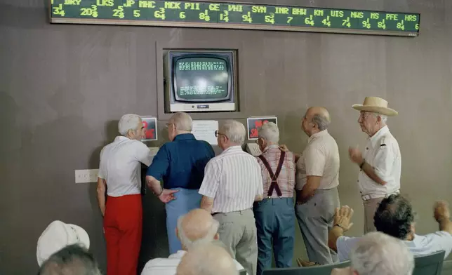 FILE - Senior citizens at First Union Brokerage Services, Inc., in the Diplomat Mall in Hallandale, Fla., keep an eye on stock market prices, Oct. 20, 1987, after Monday's market collapse. (AP Photo/Kathy Willens, File)