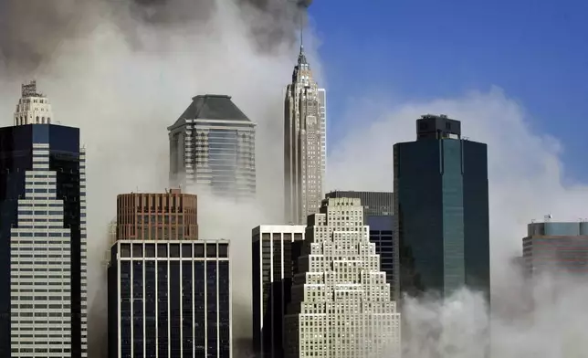 FILE - Smoke billows through buildings in Manhattan as seen from Brooklyn after the collapse of New York's World Trade Center, Sept. 11, 2001. (AP Photo/Kathy Willens, File)