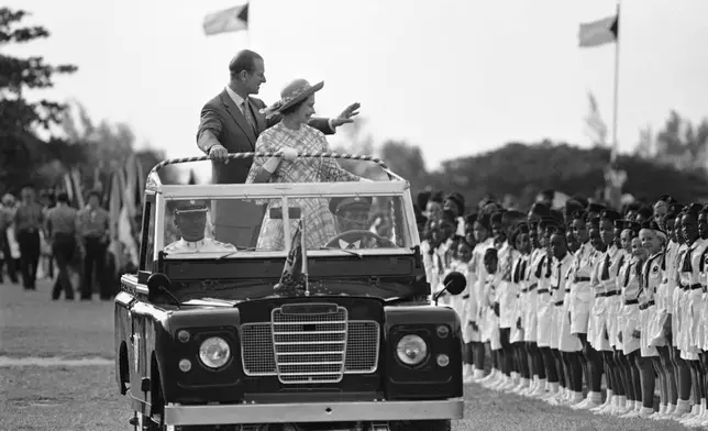 FILE - Queen Elizabeth II and Prince Philip, Duke of Edinburgh, wave to youths at Nassau's Clifford Park after their arrival in Nassau, Bahamas, on Oct. 15, 1977. (AP Photo/Kathy Willens, File)