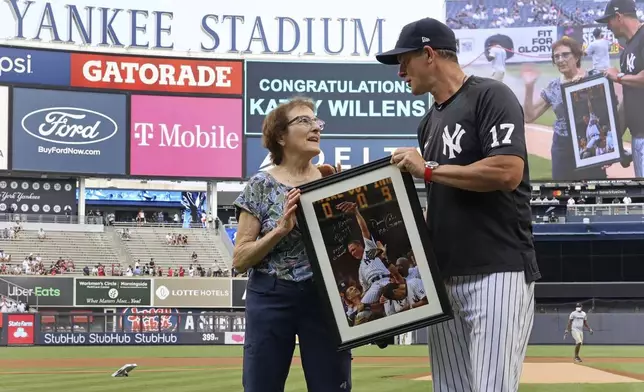 Yankees' Aaron Boone presents an autographed picture to Kathy Willens on June 28, 2021, in New York, of her picture of New York Yankees pitcher David Cone after Cone threw a perfect game. (Charles Wenzelberg/New York Post via AP)