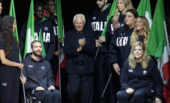 FILE - Designer Giorgio Armani accepts applause with Italy's Paralympic team at the end of the Emporio Armani men's Spring Summer 2024 collection presented in Milan, Italy, Saturday, June 17, 2023. Italian athletes will be elegantly attired in Emporio Armani uniforms, as they have for every Olympics since 2012. (AP Photo/Luca Bruno, File)