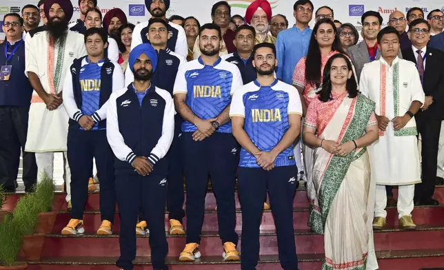 This image shared by the Public Information Bureau shows Indian athletes posing with officials as they model India's ceremonial and playing uniforms for the Paris Olympics in New Delhi, India, Sunday, June 30, 2024. (Press Information Bureau via AP)