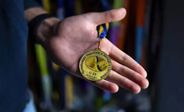 High jumper Oleh Doroshchuk holds a gold medal he won during a competition in Bakhmut, Ukraine, during an interview in his house, in Kropyvnytskyi, Ukraine, Friday, April 19, 2024. Russia occupied Bakhmut in spring of 2023 after the city was reduced to rubble in months-long grinding battle. (AP Photo/Francisco Seco)