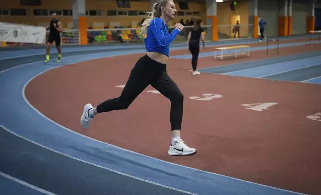 Hurdler Anna Ryzhykova trains at the sports center in Kyiv, Ukraine on Monday, Jan. 8, 2024. Ryzhykova lost a mentor who helped ignite her passion for sports. Coach Valentyn Vozniuk and his wife, Iryna Tymoshenko, were among 46 people killed by a supersonic missile that slammed into an apartment building in Dnipro in 2023. (AP Photo/Evgeniy Maloletka)