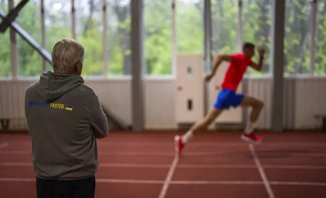 Coach Hennadii Zditovetskyi, left, watches high jumper Oleh Doroshchuk during a training session at a regional youth sport school for the Olympics, in Kropyvnytskyi, Ukraine, Thursday, April 18, 2024. Doroshchuk, one of Ukraine’s brightest prospects in Olympic track and field in Paris, has learned to ignore aid raid sirens that blare over his hometown in central Ukraine, so they don’t interrupt his training. (AP Photo/Francisco Seco)