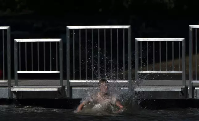 A child jumps off the dock at Cathedral City Park into the Willamette River on Friday, July 5, 2024, in Portland, Ore. A slow-moving and potentially record-setting heat wave is spreading across the Western U.S., sending many residents in search of a cool haven from the dangerously high temperatures. (AP Photo/Jenny Kane)