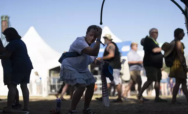 Corinne Dickey, of Portland, Ore., cools off under a mister while attending the Waterfront Blues Festival on Friday, July 5, 2024, in Portland, Ore. A slow-moving and potentially record-setting heat wave is spreading across the Western U.S., sending many residents in search of a cool haven from the dangerously high temperatures. (AP Photo/Jenny Kane)