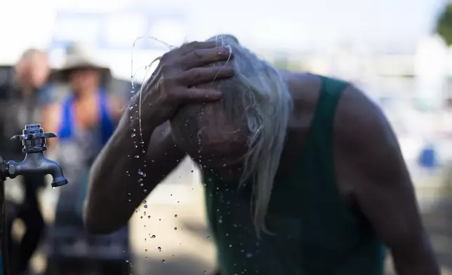 A person cools off during the Waterfront Blues Festival on Friday, July 5, 2024, in Portland, Ore. A slow-moving and potentially record-setting heat wave is spreading across the Western U.S., sending many residents in search of a cool haven from the dangerously high temperatures. (AP Photo/Jenny Kane)