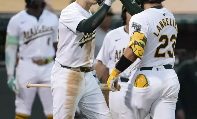 Oakland Athletics' Shea Langeliers (23) is congratulated by Zack Gelof, front left, after hitting a solo home run against the Baltimore Orioles during the seventh inning of a baseball game Friday, July 5, 2024, in Oakland, Calif. (AP Photo/Godofredo A. Vásquez)