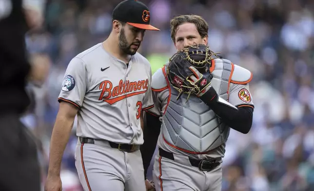 Baltimore Orioles starting pitcher Grayson Rodriguez, left, and catcher Adley Rutschman walk off the field at the end of the first inning of a baseball game against the Seattle Mariners, Tuesday, July 2, 2024, in Seattle. (AP Photo/Stephen Brashear)