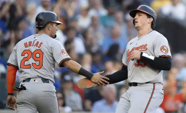 Baltimore Orioles' Ramon Urias, left, and Adley Rutschman celebrate after scoring runs during the third inning of a baseball game against the Seattle Mariners, Wednesday, July 3, 2024, in Seattle. (AP Photo/Stephen Brashear)