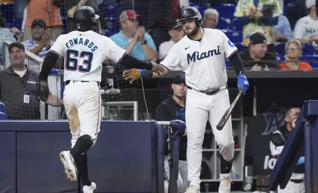 Miami Marlins' Jake Burger, right, congratulates Xavier Edwards (63) after Edwards and Nick Gordon scored on a double by Jazz Chisholm Jr., during the seventh inning of a baseball game against the Baltimore Orioles, Wednesday, July 24, 2024, in Miami. (AP Photo/Wilfredo Lee)