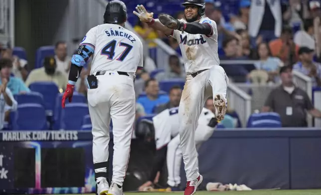 Miami Marlins' Ali Sánchez (47) congratulates Otto Lopez after Lopez scored on a sacrifice fly by Nick Gordon during the fourth inning of a baseball game against the Baltimore Orioles, Wednesday, July 24, 2024, in Miami. (AP Photo/Wilfredo Lee)