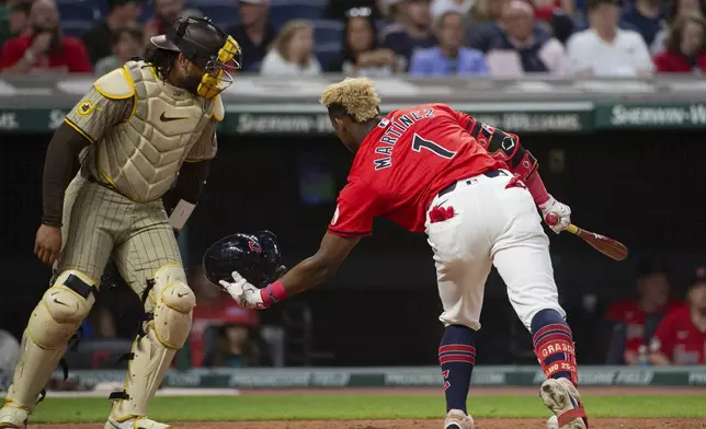 Cleveland Guardians' Angel Martinez (1) catches his helmet after it fell off during a swing as San Diego Padres' Luis Campusano, left, looks on during the seventh inning of a baseball game in Cleveland, Saturday, July 20, 2024. (AP Photo/Phil Long)