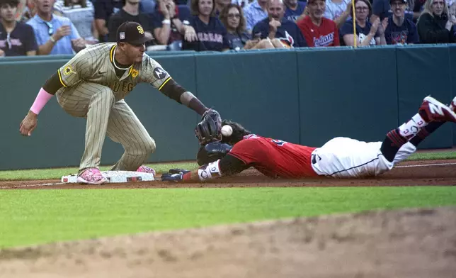 San Diego Padres' Manny Machado, left, does not get a throw in time to tag out Cleveland Guardians' Tyler Freeman, right, who is safe at third base with a triple during the third inning of a baseball game in Cleveland, Saturday, July 20, 2024. (AP Photo/Phil Long)