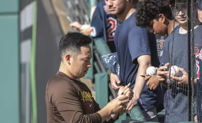 San Diego Padres relief pitcher Yuki Matsui, left, gives autographs to fans before a baseball game against the Cleveland Guardians in Cleveland, Saturday, July 20, 2024. (AP Photo/Phil Long)