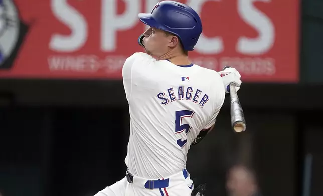 Texas Rangers' Corey Seager follows through on a run-scoring double against the San Diego Padres in the third inning of a baseball game, Wednesday, July 3, 2024, in Arlington, Texas. Marcus Semien scored on the hit. (AP Photo/Tony Gutierrez)