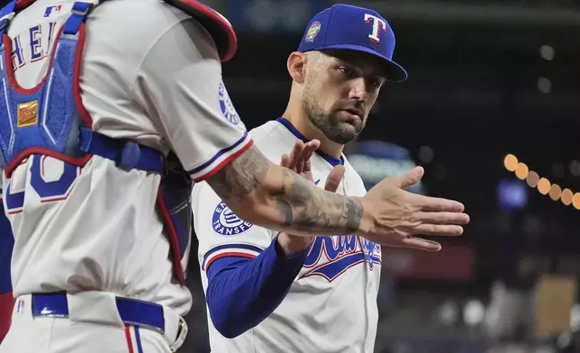 Texas Rangers starting pitcher Nathan Eovaldi, right, gets a congratulatory hand from teammate catcher Jonah Heim (28) after the third out during the seventh inning of a baseball game against the San Diego Padres in Arlington, Texas, Tuesday, July 2, 2024. (AP Photo/LM Otero)