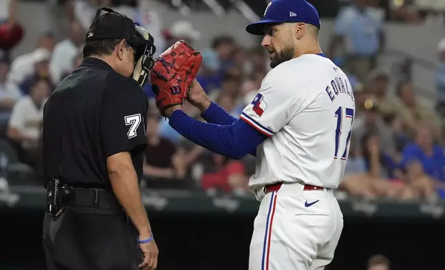 Texas Rangers starting pitcher Nathan Eovaldi (17) asks for a clarification of a call by home plate umpire Alfonso Marquez (72) during the seventh inning of a baseball game against the San Diego Padres in Arlington, Texas, Tuesday, July 2, 2024. (AP Photo/LM Otero)