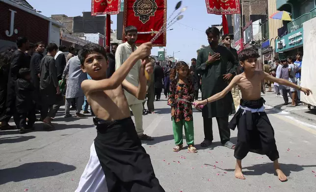 Shiite Muslim boys flagellate themselves with knifes attached to chains during a Muharram procession, in Peshawar, Pakistan, Tuesday, July 16, 2024. Muharram, the first month of the Islamic calendar, is a month of mourning for Shiites in remembrance of the death of Hussein, the grandson of the Prophet Muhammad, at the Battle of Karbala in present-day Iraq in the 7th century. (AP Photo/Muhammad Sajjad)