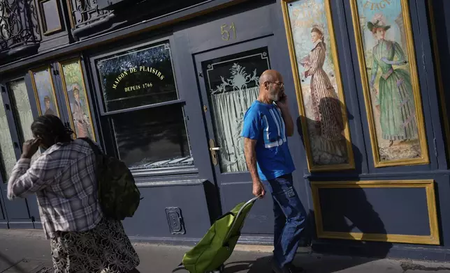 People walk past a restaurant decorated with artwork, ahead of the 2024 Summer Olympics, Monday, July 22, 2024, in Paris, France. (AP Photo/Rebecca Blackwell)