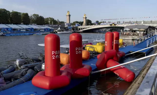 Buoys sit along the Seine river as the triathlon event venue on the Pont Alexandre III bridge stands in the background at the 2024 Summer Olympics, Monday, July 29, 2024, in Paris. As the Olympics continue in Paris, the Seine River's water quality remains a major area of concern for officials. Organizers of the triathlon event cancelled swimming practice on Monday for the second day in a row because of poor water quality. Event organizers hope sunny weather will make swimming viable on Tuesday when the triathlon begins. (AP Photo/David Goldman)