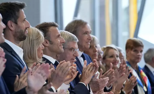 IOC President Thomas Bach, center, French President Emmanuel Macron, center left, his wife Brigitte Macron, third left, and LVMH CEO Bernard Arnault, centre right, applaud during the IOC Session Opening Ceremony at the Louis Vuitton Foundation ahead of the 2024 Summer Olympics, Monday, July 22, 2024, in Paris, France. (AP Photo/Thibault Camus)