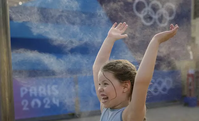 Charlotte, 6, from Germany, plays with a misting fountain on a hot afternoon during the 2024 Summer Olympics, Monday, July 29, 2024, in Paris, France. (AP Photo/Vadim Ghirda)