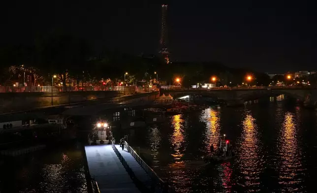 Technicians remove the pontoon for the start of the triathlon events after the event was postponed over concerns about water quality in Paris' Seine River, at the 2024 Summer Olympics, Tuesday, July 30, 2024, at the Pont Alexandre III bridge in Paris, France. (AP Photo/Yasin Dar)