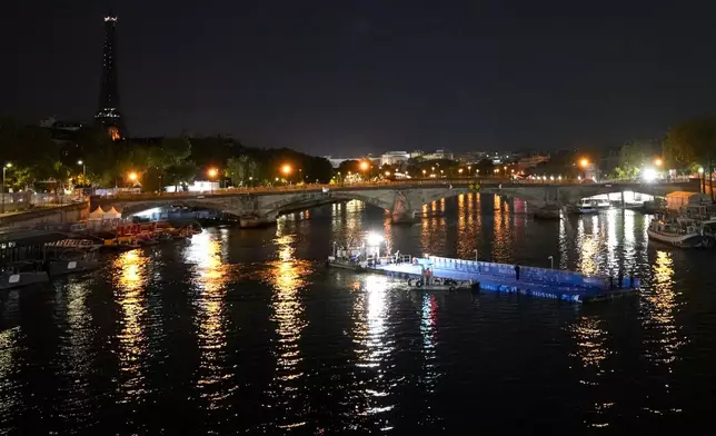 Technicians remove the pontoon for the start of the triathlon events after the event was postponed over concerns about water quality in Paris' Seine River, at the 2024 Summer Olympics, Tuesday, July 30, 2024, at the Pont Alexandre III bridge in Paris, France. (AP Photo/Yasin Dar)