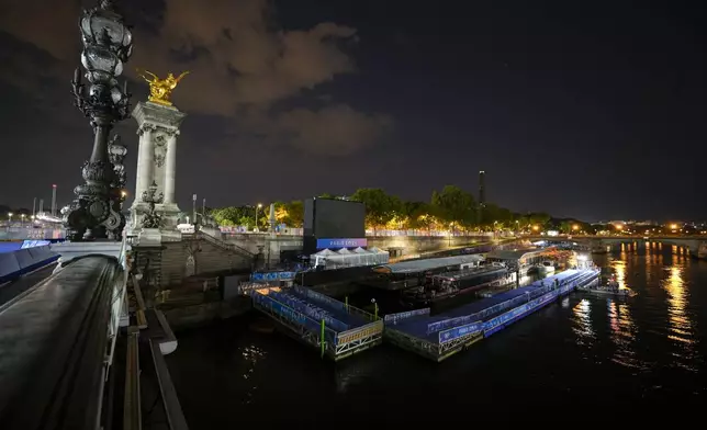 Technicians remove the pontoon for the start of the triathlon events after the event was postponed over concerns about water quality in Paris' Seine River, at the 2024 Summer Olympics, Tuesday, July 30, 2024, at the Pont Alexandre III bridge in Paris, France. (AP Photo/Vadim Ghirda)